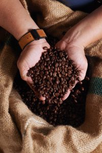 unrecognizable man holding handful coffee beans